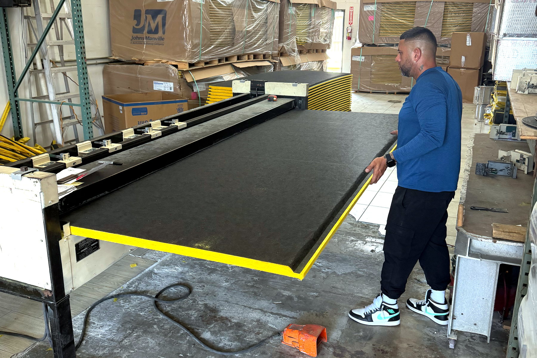 Banos HVAC team member cutting duct board on the shop fabrication table