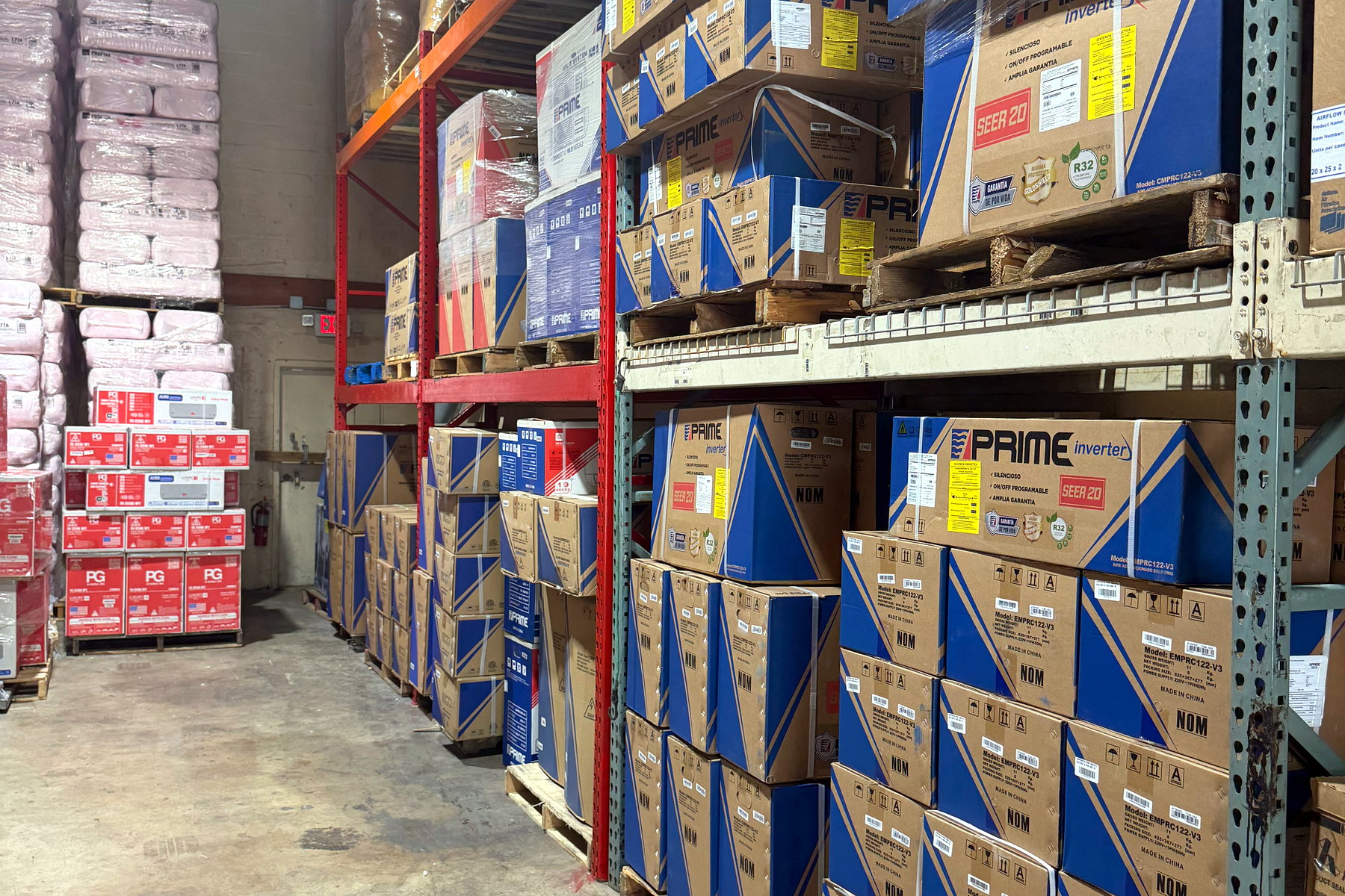 Warehouse aisle at Banos HVAC stacked floor to ceiling with boxed condensing units